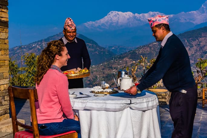 Breakfast served on the patio of the Tiger Mountain Pokhara Lodge with three peaks of the Annapurna Massif (Annapurna South, Annapurna 1 and Hiunchuli) in the background. Lekhnath, near Pokhara, Nepal.